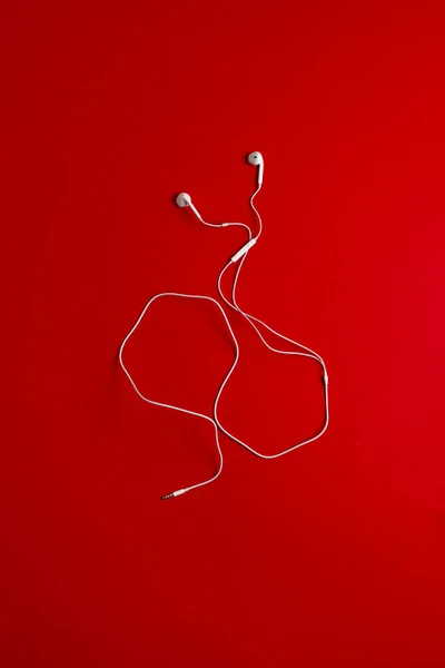 A view from above of the white wired simple earbuds earphones flat lay on the colorful background isolated — Stock Photo, Image