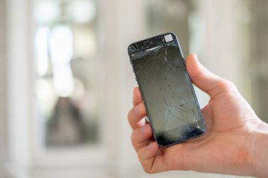 Bozuk bir telefon ve cep telefonu tutan kişilerin elleri...