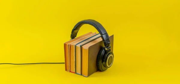 听有声读物的概念，把大耳机放在书架上孤立，简朴的风格 — 图库照片