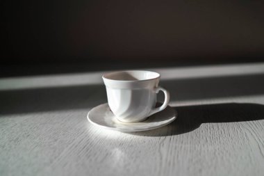 soyut beyaz bardak sıcak içecek tabakta sabah beyaz masa, sert güneş ve gölgeler