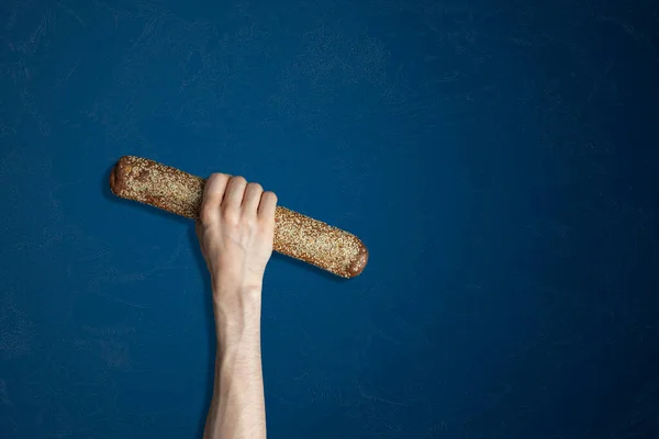 Una mano isolata che tiene una baguette di pane fresco sullo sfondo di colore — Foto Stock