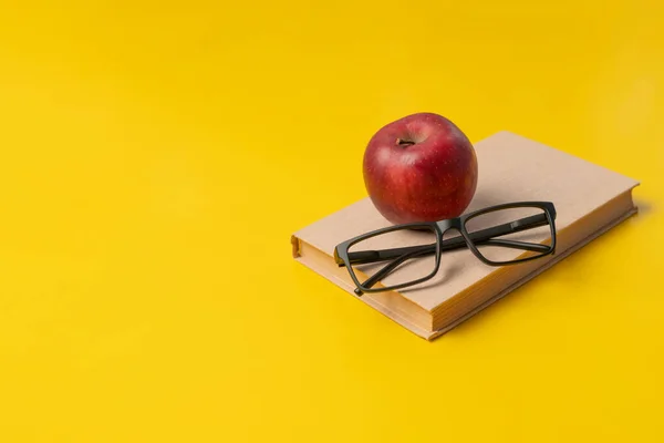 Bücherstapel, roter Apfel und Gläser isoliert auf bunter Oberfläche, einfaches abstraktes Studienkonzept — Stockfoto