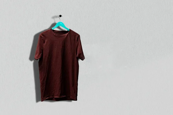 Uma simples camiseta de algodão no cabide pendurar na parede, roupas abstratas com espaço de cópia — Fotografia de Stock