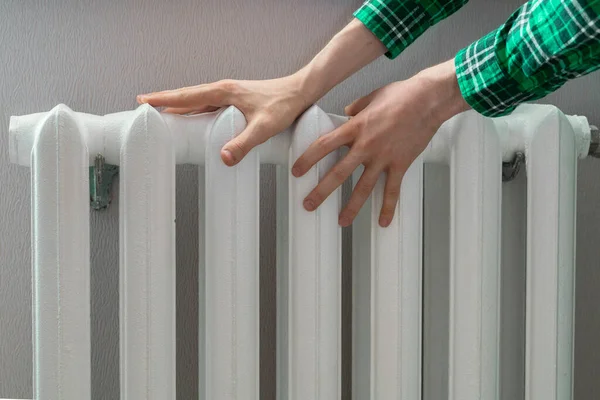 The frozen hands touch a heating battery at home during winter season — Stock Photo, Image