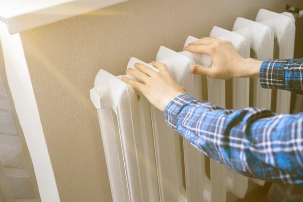 As mãos congeladas tocam uma bateria de aquecimento em casa durante a temporada de inverno — Fotografia de Stock