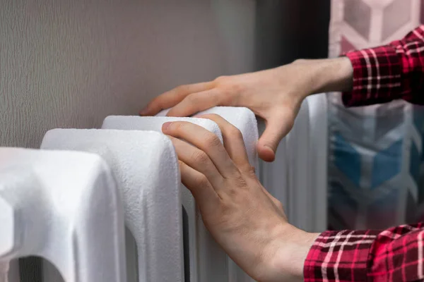 Las manos congeladas tocan una batería de calefacción en casa durante la temporada de invierno —  Fotos de Stock