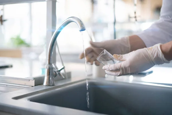 Een persoon handen in handschoenen reinigen en wassen glazen kolven met water in het laboratorium — Stockfoto