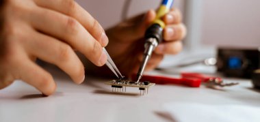 Elektrik parçalarını lehimleyen mühendisin yakın plandaki görüntüsü.