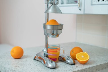 Evdeki mutfak masasında kesilmiş portakallar ve camlarla birlikte çelik metal pres sıkacağı.