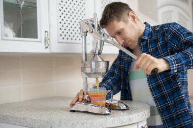 Sabah kahvaltısı, bir adam metal baskı makinesiyle taze portakal suyu yapıyor.