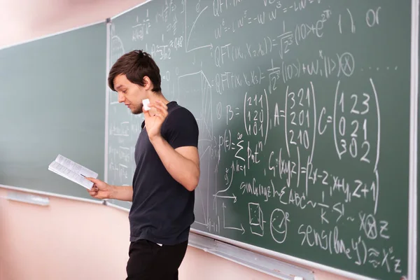 Молодой студент университета, стоящий рядом с доской и размышляющий над уравнением математики — стоковое фото