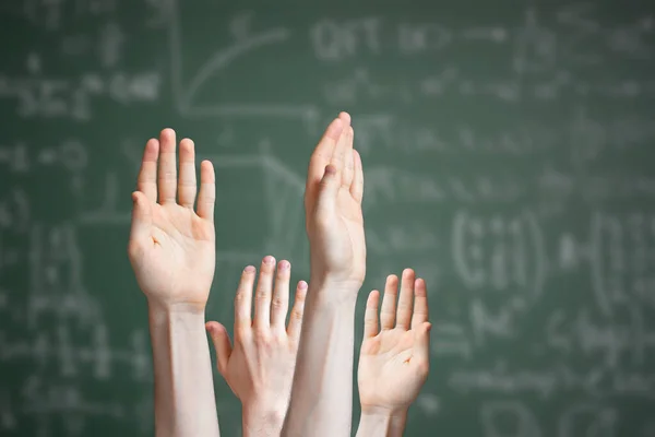 Un grupo de alumnos levantan la mano y quieren responder a la pregunta de los profesores, pizarra fondo — Foto de Stock