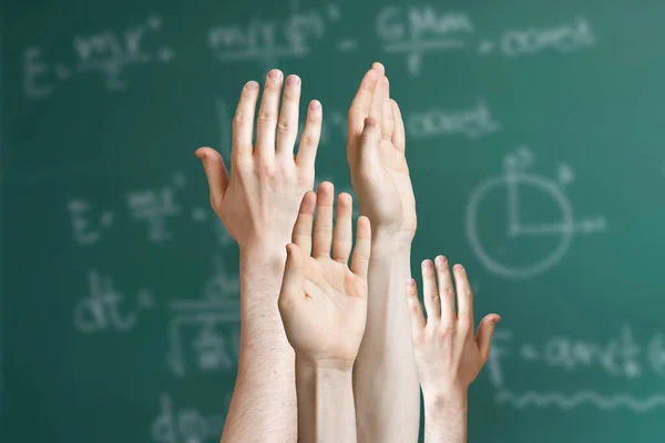 Um grupo de alunos levantar a mão e quer responder à pergunta professores, fundo quadro negro — Fotografia de Stock