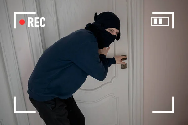 Rikollisuus murtovaras musta naamio yrittää rikkoa oven talon asuntoja, salainen CCTV kamerajärjestelmä — kuvapankkivalokuva