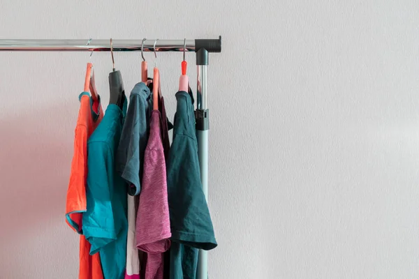 Um conjunto simples de camisetas coloridas em um cabide em casa perto da parede, conceito minimalista simples — Fotografia de Stock