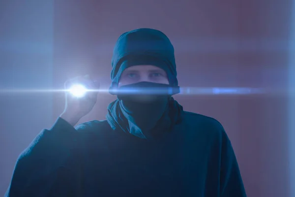 Um ladrão de bandidos de perto na máscara com uma luz de tocha enquanto faz um crime — Fotografia de Stock