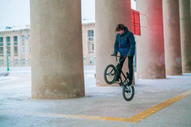 Delikanlı erkek BMX bisikleti üzerinde numaralar yapıyor ve B kolu kullanmıyor.