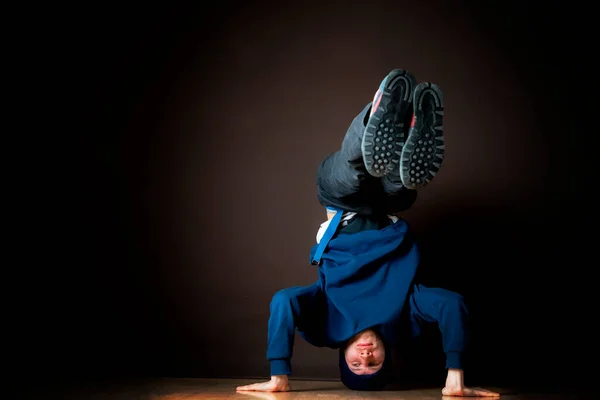 Hip hop tancerz wykonać headstand do góry nogami w ciemnym studio b — Zdjęcie stockowe