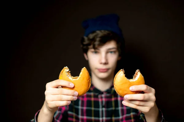 Samec drží pokousaný cheeseburger a vášnivě ho jí f — Stock fotografie