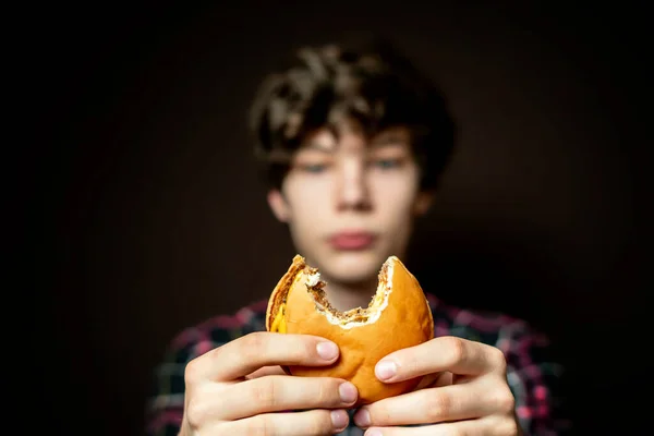 Male holding a bitten cheeseburger and passionately eating it f Stock Image