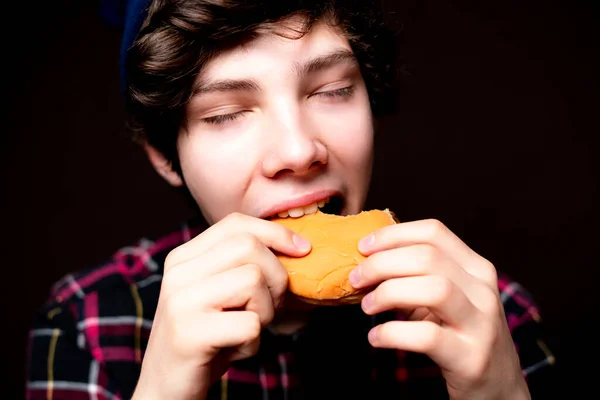 Closeup photo of mouth bite junk hamburger on dark background isolated b Stock Photo