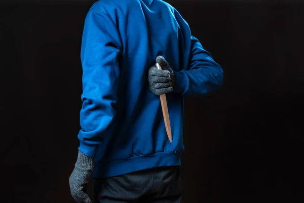 Maniak w rękawiczkach trzymać ostry nóż za plecami i w kieszeni jest bolated — Zdjęcie stockowe