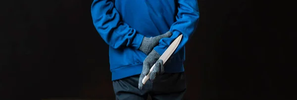 Maniak w rękawiczkach trzymać ostry nóż za plecami i w kieszeni jest bolated — Zdjęcie stockowe