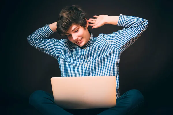 Retrato de joven feliz guapo sentarse en el uso del suelo portátil y usar camisa a cuadros y pantalones b — Foto de Stock