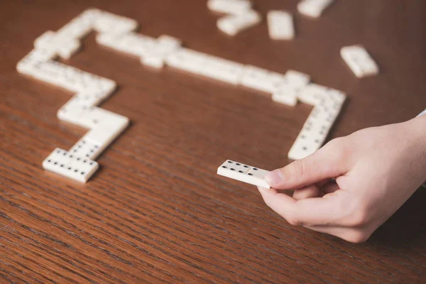 Fechar a mão segurar peça dominó na mesa de madeira f — Fotografia de Stock