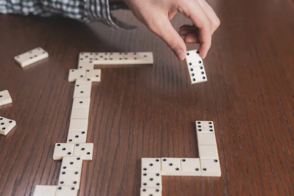 Fechar a mão segurar peça dominó na mesa de madeira f — Fotografia de Stock