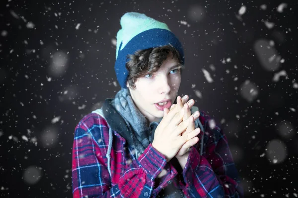 Nuori uros jäätyy ja pukeutuu lämpimiin vaatteisiin kylmänä lumisena päivänä b — kuvapankkivalokuva