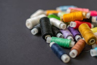 Bir demet renkli dikiş ipliği koyu arkaplanda izole bir şekilde duruyordu.