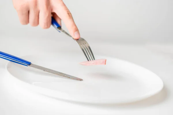 Persona manos con tenedor y cuchillo comer pequeña porción de comida. anorexia b — Foto de Stock