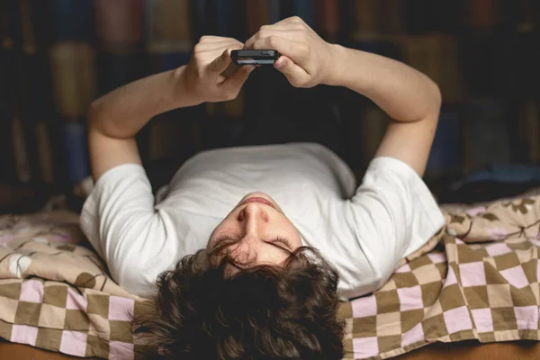Junger Mann lag kopfüber auf Bett und plauderte in seinem Handy-Gadget — Stockfoto