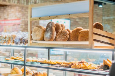 Fırıncı dükkanındaki tezgahın üzerinde çeşitli taze ekmek türleri var.