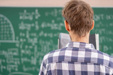 Mutlu genç konuşmacı portresi kara tahtanın önünde ders veriyor.