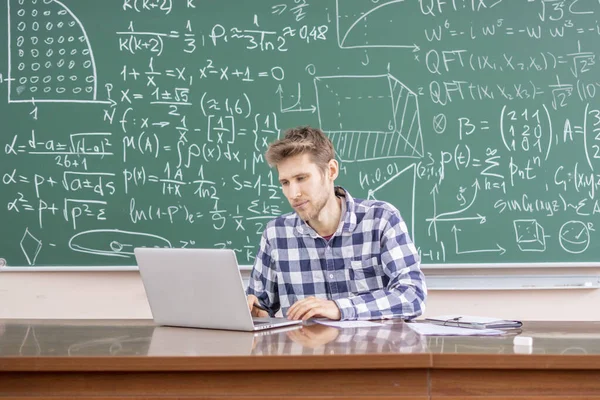 Молодой учитель, работающий с ноутбуком или читающий онлайн лекцию b — стоковое фото