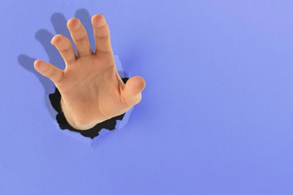 Uma mão humana alcançar o objetivo, levantar através do buraco em papel colorido — Fotografia de Stock