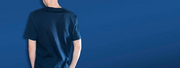 Homem no escuro azul t-shirt mockup e copiar espaço contra o fundo da parede de cor, sem rosto — Fotografia de Stock