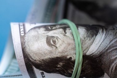 Lastik bandın ördüğü 100 dolarlık kağıt para rulosunu kapat.