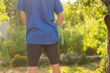 rear view of young person standing outdoor and piss under the trees