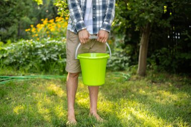 Saf sularla dolu renkli bir kova tutuyordu.