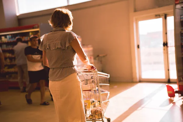 Женщина с тележкой в продуктовом магазине — стоковое фото