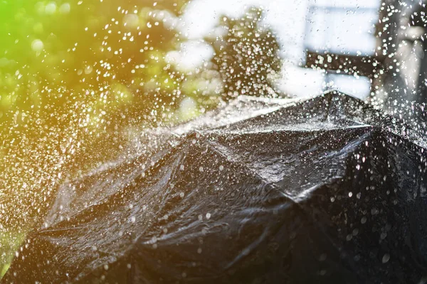 Cerrar paraguas negro con salpicaduras y gotas de lluvia durante las fuertes lluvias al aire libre — Foto de Stock