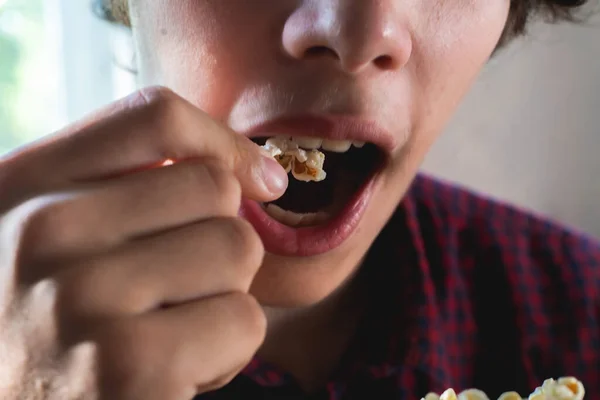 Primer plano joven macho sosteniendo palomitas de maíz para ponerlo en su boca — Foto de Stock