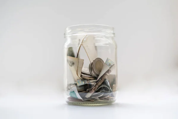 Un banco de vidrio con monedas de dinero de ceniza y papel uno —  Fotos de Stock