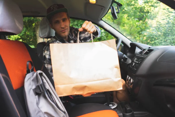 Messager assis à l'intérieur de la voiture et se déplacer vers le client pour donner les paquets Photos De Stock Libres De Droits