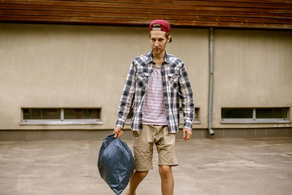 Młody człowiek zabiera worek na śmieci. — Zdjęcie stockowe