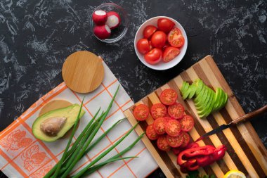 Kesme tahtasına, domatese, avokadoya, biberlere doğranmış taze organik sebzeleri kapatın.