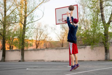 Basketbolcu şehir kortlarında atış talimi yapıyor.